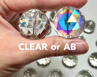 Könnte beinhalten: Zwei runde facettierte Kristallperlen, eine klar und eine mit irisierendem Aurora-Borealis-Finish, mit geometrischen Schliffen. Der Text CLEAR or AB ist in der Mitte zu sehen, darunter sind weitere klare Perlen verstreut.