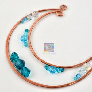 May include: Copper wire crescent moon shape with blue and clear glass beads. The moon has a loop at the top for hanging.