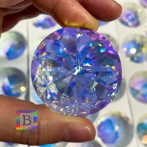 May include: A clear iridescent crystal prism with a faceted design. The prism is round and has a hole in the top for hanging. The prism is reflecting rainbow colours.