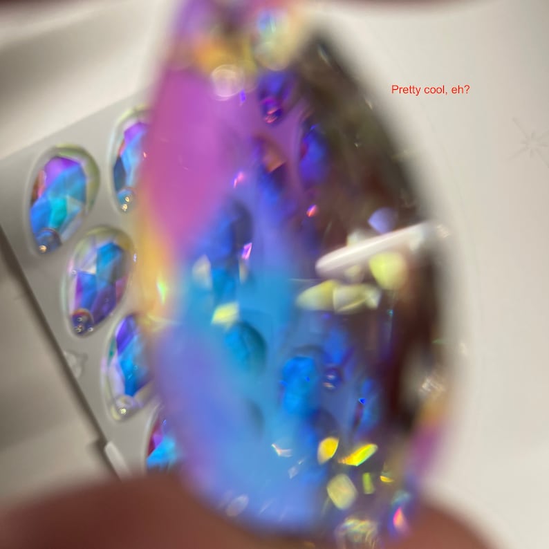 May include: A close-up of a iridescent blue and purple gemstone with a textured surface. The gemstone is surrounded by smaller, iridescent gemstones.