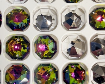 Puede incluir: Primer plano de una bandeja blanca llena de piedras de cristal octogonales iridiscentes. Las piedras de cristal tienen un efecto arcoíris con tonos de verde, morado y dorado.
