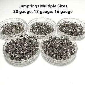 May include: Five clear plastic containers filled with silver jump rings of varying sizes. The text "Jumprins Multiple Sizes 20 gauge, 18 gauge, 16 gauge" is printed at the top of the image.