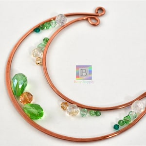 May include: Copper wire crescent moon shape with green, clear, and gold beads attached.