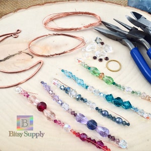 May include: A set of jewelry making supplies including copper wire, crystal beads, and pliers. The beads are arranged in rainbow colors on a wooden surface. The text "Bitsy Supply" is visible in the bottom left corner of the image.