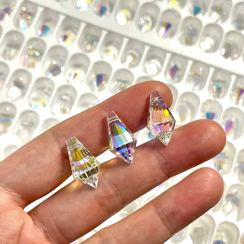 Peut inclure: Trois pendentifs en cristal iridescent en forme de larme de diff&eacute;rentes tailles. Les cristaux sont transparents avec un effet arc-en-ciel.