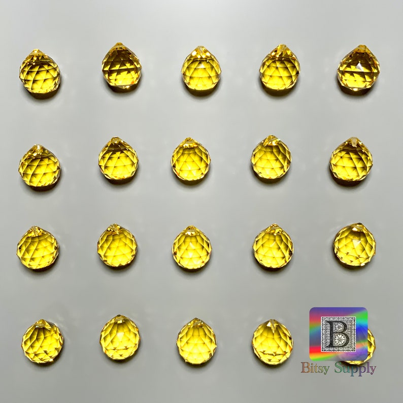May include: Twenty yellow crystal teardrop prisms, each with a faceted design, arranged in a grid pattern on a white background. The image includes the text "Bitsy Supply" in the bottom right corner.