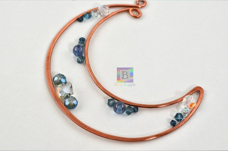 May include: Copper wire crescent moon with blue and clear glass beads. The crescent moon is made of two pieces of wire, one inside the other. The beads are scattered around the moon.