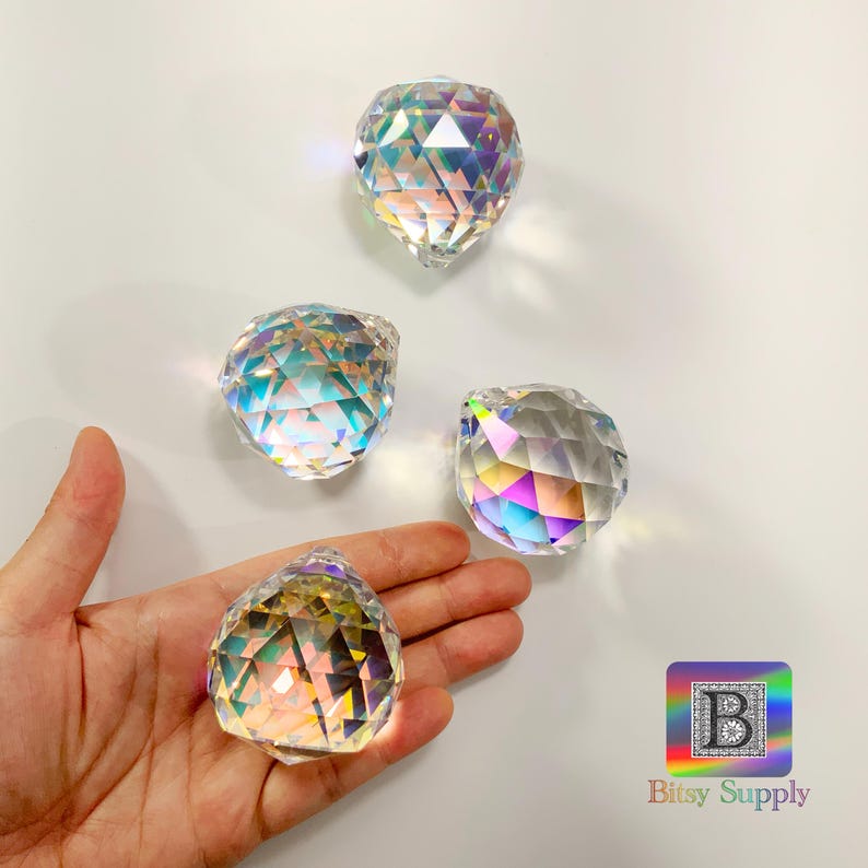 K&ouml;nnte beinhalten: Vier regenbogenfarbene Kristallkugeln mit facettierten Oberfl&auml;chen. Die Kristalle sind klar mit Regenbogenreflexen.