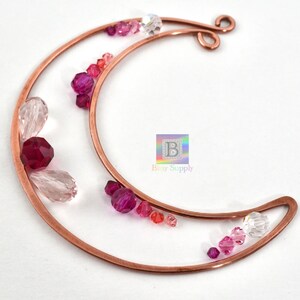 May include: A copper wire crescent moon shape with pink, red, and clear glass beads attached. The crescent moon is made of copper wire and has a loop at the top for hanging.