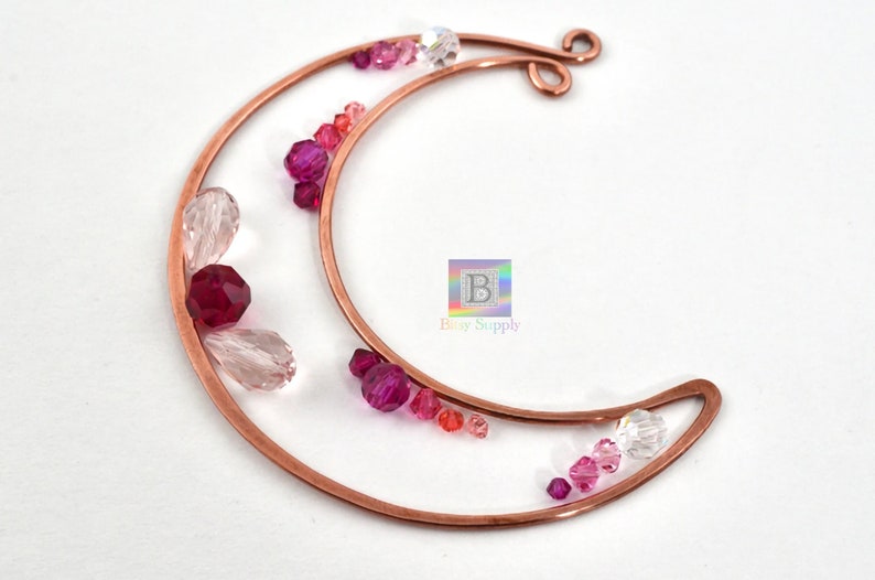 May include: A copper wire crescent moon shape with pink, red, and clear glass beads attached. The crescent moon is made of copper wire and has a loop at the top for hanging.