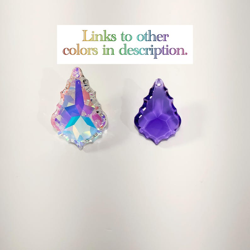 Peut inclure: Deux pendentifs d&eacute;coratifs en cristal. L'un est iris&eacute; avec des accents roses et argent&eacute;s. L'autre est de couleur violette unie. Le texte "Liens vers d'autres couleurs dans la description" est au-dessus des pendentifs.