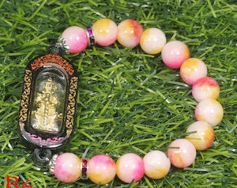 May include: A pink and yellow beaded bracelet with a gold charm in a black frame. The charm is a small statue of a person with a crown.