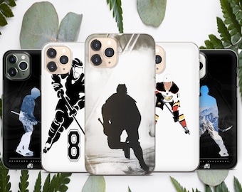 May include: Four different phone cases with hockey player designs. The cases are white with black and grey designs. One case features a silhouette of a hockey player, another features a hockey player with a number 8 on their jersey, another features a hockey player in a red, black, and white jersey, and the last case features a silhouette of a hockey player in front of a mountain scene.