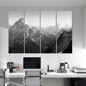 Pu&ograve; includere: Una fotografia in bianco e nero di una catena montuosa con cime innevate. La foto &egrave; divisa in quattro pannelli ed &egrave; esposta su una parete sopra una scrivania con un computer, una stampante e materiale da ufficio.