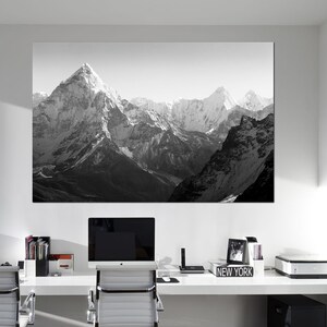 Pu&ograve; includere: Una fotografia in bianco e nero di una catena montuosa con cime innevate. La foto &egrave; appesa a una parete bianca in un ufficio moderno.
