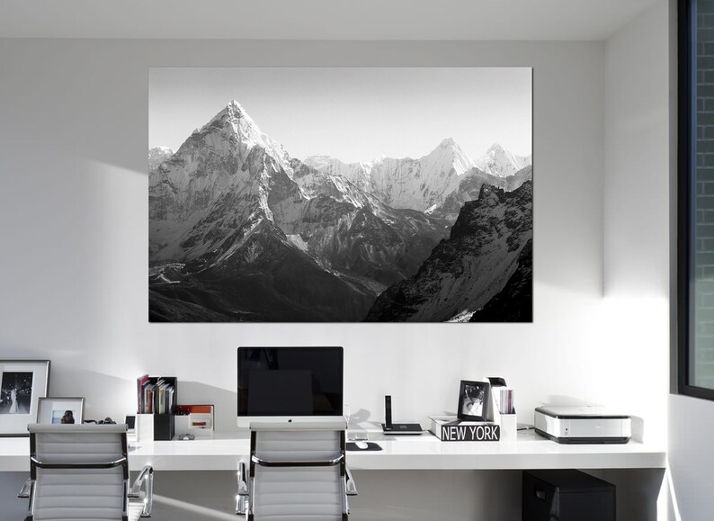 Pu&ograve; includere: Una fotografia in bianco e nero di una catena montuosa con cime innevate. La foto &egrave; appesa a una parete bianca in un ufficio moderno.