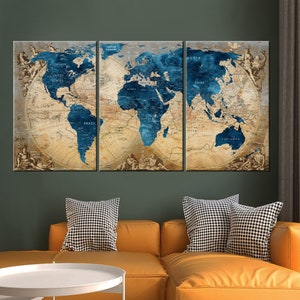 May include: A three-piece canvas print set featuring a vintage world map with blue oceans and continents in beige and brown tones. The map is surrounded by a decorative border with ornate details. The prints are displayed on a wall above a yellow couch with black and white patterned throw pillows.