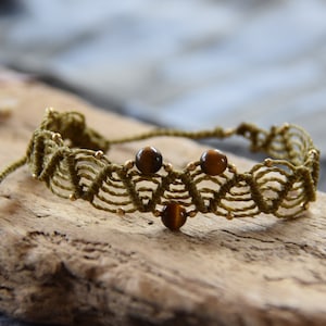 May include: A green macrame bracelet with three brown tiger's eye beads.