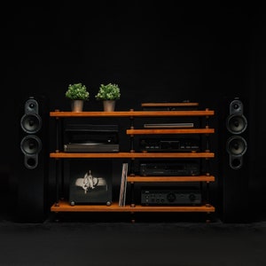 May include: A black wooden stereo system with two speakers, a turntable, a CD player, and a receiver. The system is on a wooden shelf with two plants on top.
