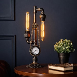 Op de afbeelding: Steampunk tafellamp met zichtbare Edison-lampen. De lamp heeft een donker metalen pijpontwerp met een manometer en kettingaccenten. De basis is gemaakt van tandwielen en de lampen geven een warme gloed. Een kleine plant in een pot en een boek staan op de tafel.