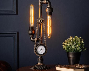 May include: Steampunk-style table lamp with exposed Edison bulbs. The lamp features a dark metal pipe design with a pressure gauge and chain accents. The base is made of gears, and the bulbs emit a warm, inviting glow. A small potted plant and a book are on the table.