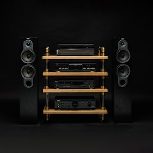 May include: A black stereo system with a turntable, CD player, amplifier, and two speakers on a wooden shelf unit with gold accents.