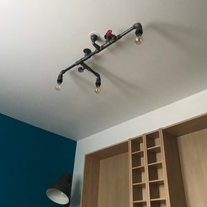 May include: A black industrial pipe light fixture with four light bulbs and a red valve. The fixture is mounted on a white ceiling.