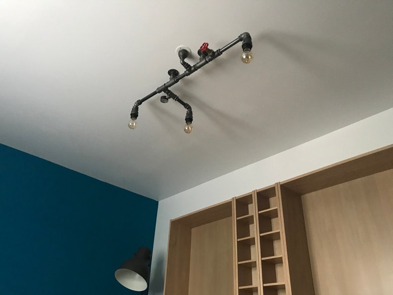 May include: A black industrial pipe light fixture with four light bulbs and a red valve. The fixture is mounted on a white ceiling.