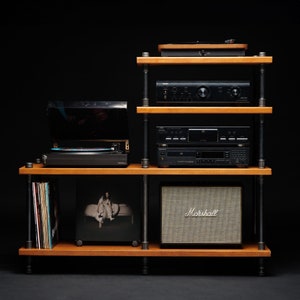 May include: A black wooden shelf unit with four shelves, holding a turntable, a stereo receiver, a CD player, a speaker, and vinyl records. The shelf unit has black metal legs and is on a black background.