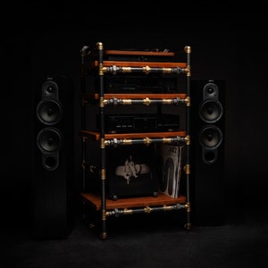 May include: A black metal shelf unit with wooden shelves, holding a turntable, stereo receiver, and a record player. Two black speakers flank the shelf unit.