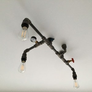 May include: A black metal pipe light fixture with four Edison bulbs and a red valve. The fixture is mounted to a white ceiling.