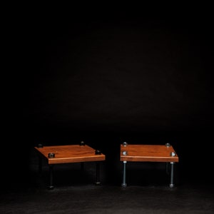 May include: Two small wooden platforms with metal legs. The platforms are made of dark wood and have a square shape. The metal legs are attached to the bottom of the platforms and are made of silver metal.