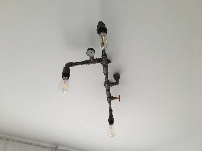May include: A ceiling light fixture made of black metal pipes with three light bulbs. The fixture has a gauge and a red valve.
