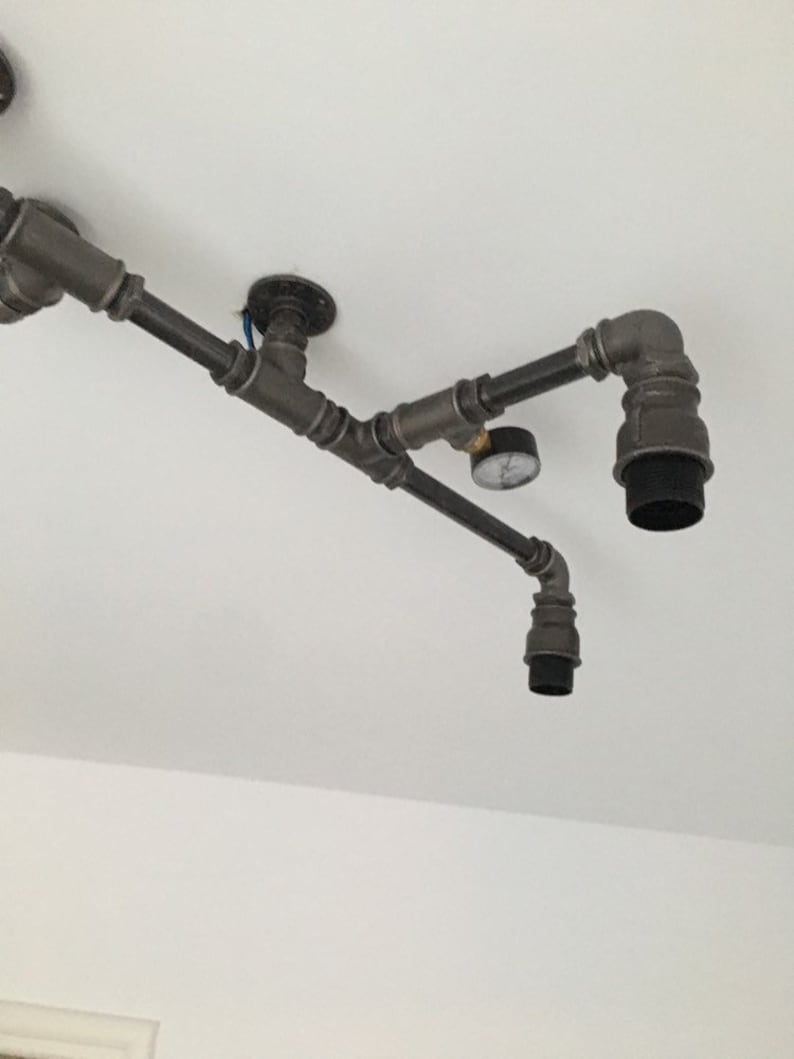 May include: A black industrial style pipe light fixture with two black light sockets and a small gauge attached to the pipe.