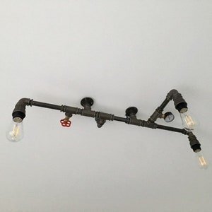 May include: A black metal pipe light fixture with four exposed light bulbs. The fixture has a red valve and a gauge.