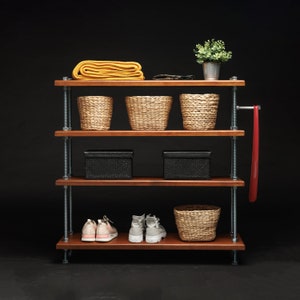 May include: A four-tiered metal shelf unit with wooden shelves. The shelves are filled with various items, including baskets, boxes, shoes, and a plant.