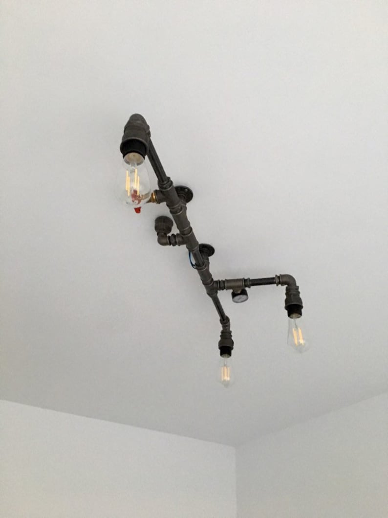 May include: A black metal pipe light fixture with four exposed light bulbs. The fixture is mounted to a white ceiling.