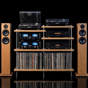 May include: A high-fidelity audio system featuring two tall light wood speakers, a multi-tier wooden rack with metal supports, two Technics turntables, two McIntosh amplifiers with blue illuminated meters, and two Accuphase units, all filled with vinyl records.
