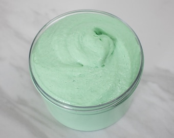 May include: A close-up of a light green slime in a clear plastic container. The slime is smooth and has a swirl pattern.
