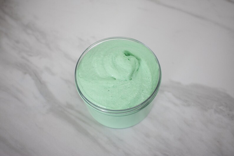 May include: A close-up of a light green slime in a clear plastic container. The slime is smooth and has a swirl pattern.