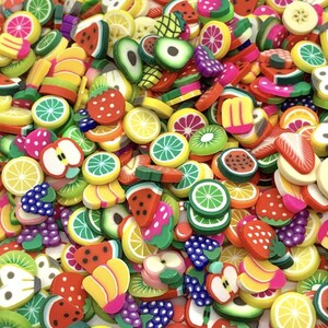 May include: A vibrant assortment of colorful fruit slices, including watermelon, strawberries, lemons, kiwi, and bananas. The miniature fruit shapes are in various sizes and are scattered across the image, creating a playful and cheerful display.