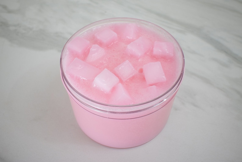 May include: Pink slime with white square-shaped pieces inside a clear plastic container.