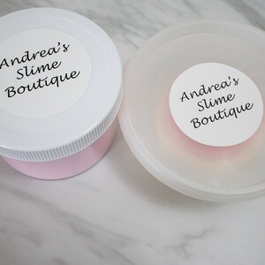 May include: Two white plastic containers with pink slime inside. The containers have white lids with black text that reads "Andrea's Slime Boutique."