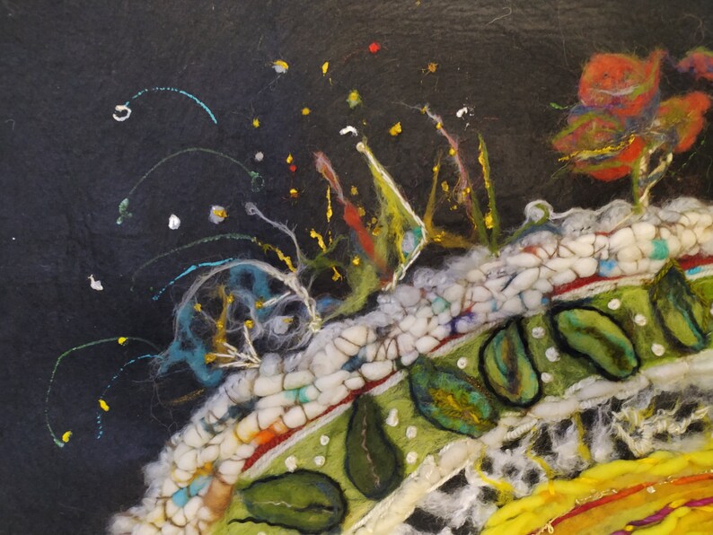 Op de afbeelding: Een close-up van een kleurrijk viltkunstwerk met een textuur. Het kunstwerk heeft een verscheidenheid aan kleuren, waaronder wit, zwart, groen, rood en geel. Het kunstwerk is gemaakt van kleine stukjes vilt die aan elkaar zijn genaaid om een uniek ontwerp te cre&euml;ren.