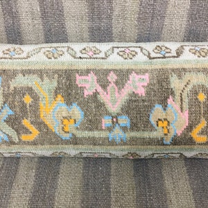 May include: Close-up of a brown and beige patterned rug with a floral design. The rug has a fringe border and is made of wool.