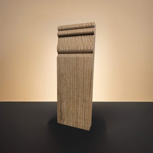 May include: A light brown wood baseboard with a decorative molding detail. The baseboard has a natural wood grain pattern.