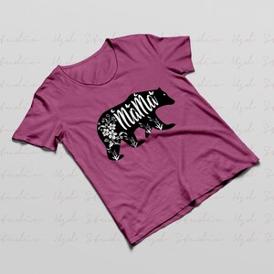 May include: A pink t-shirt with a black bear silhouette. The bear has floral details and the word "Mama" written inside the silhouette.