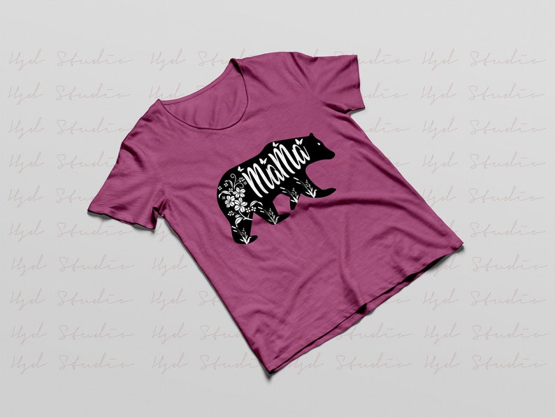May include: A pink t-shirt with a black bear silhouette. The bear has floral details and the word "Mama" written inside the silhouette.