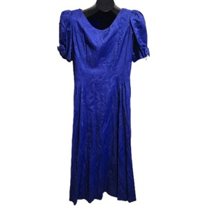 May include: A vibrant blue dress with short, puffed sleeves and a scoop neckline. The dress features a fitted bodice and a flowing skirt, creating an elegant silhouette. The fabric has a subtle sheen, adding to its formal appearance. The dress is displayed on a black hanger.