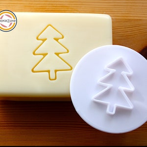 Könnte beinhalten: Weißer Weihnachtsbaum-Ausstecher aus Kunststoff auf weißem Hintergrund. Der Ausstecher hat die Form eines einfachen Weihnachtsbaums mit drei Stufen.